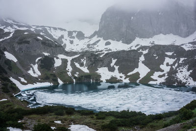 Scenic view of lake by snowcapped mountains against sky