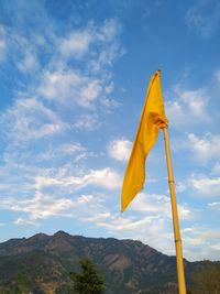 Low angle view of yellow flag against sky