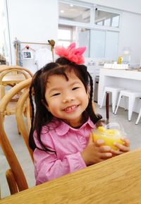 Portrait of smiling cute girl sitting at table