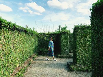 Portrait of woman walking amidst mossy wall