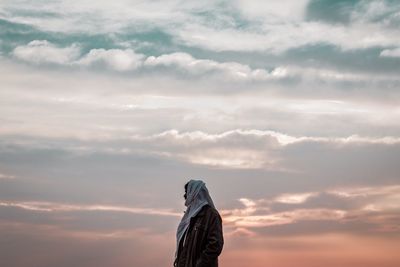 Woman standing against sky during sunset