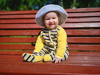 Portrait of cute baby girl sitting on bench