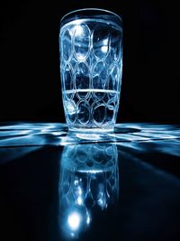 Glass of water on table against black background