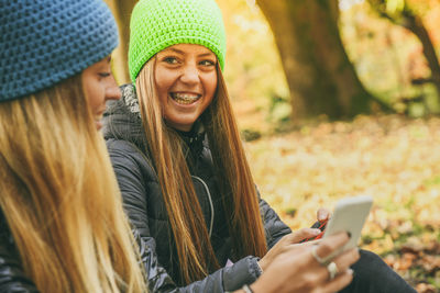 Girls with wool cap sitting in the park using smartphone. teen using mobile phone chat with friends