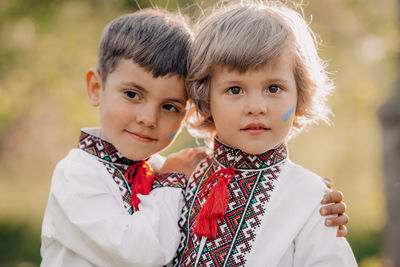 Boy embracing brother with ukraine flag on face