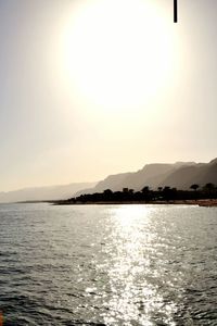 Scenic view of sea and mountains against clear sky