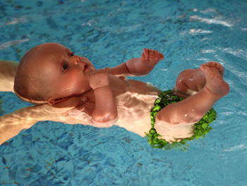 High angle view of cropped hand holding baby on swimming pool