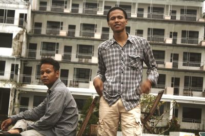 Happy young man standing against window