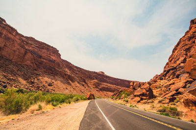 Road leading towards mountains against sky