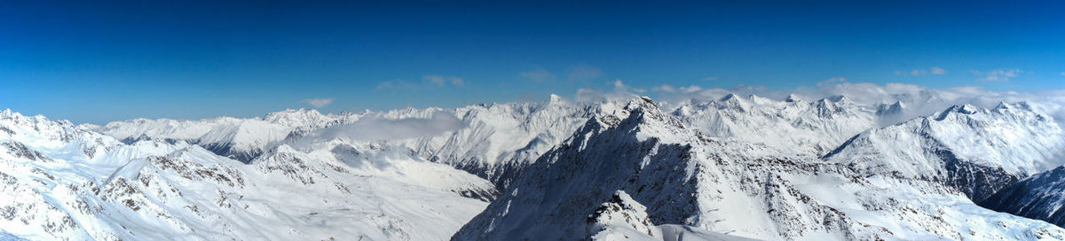 Panoramic view of snowcapped mountains against blue sky