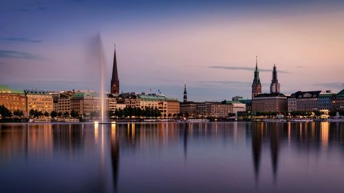 Binnenalster lake by buildings against sky during sunset in city