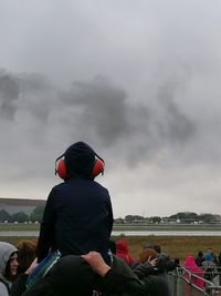 Rear view of father carrying son on shoulders against smoke