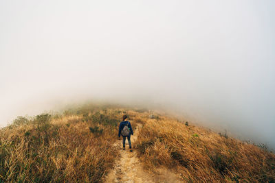 Rear view of woman walking on mountain against sky