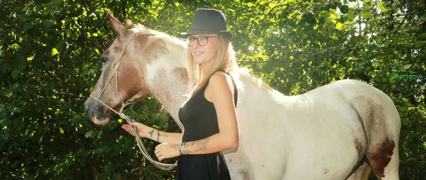 Young woman with horse standing in ranch