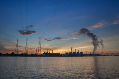 Smoke emitting from factory against sky during sunset