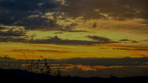 Low angle view of dramatic sky over silhouette landscape