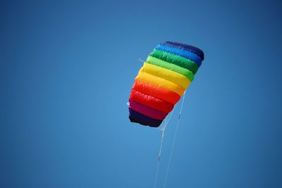 Low angle view of multi colored parachute against clear blue sky