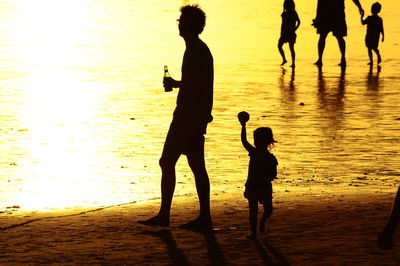 Silhouette people at beach during sunset