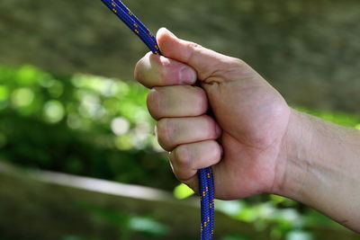 Cropped hand holding rope