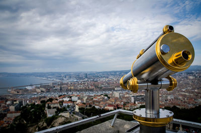 Close-up of hand-held telescope against cityscape