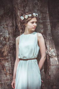 Young woman standing against tree