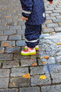 Low section of woman standing on cobblestone street
