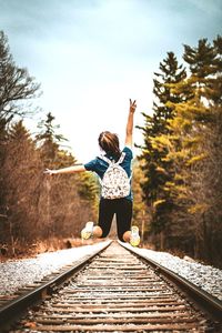 Rear view of teenage girl jumping on railroad track