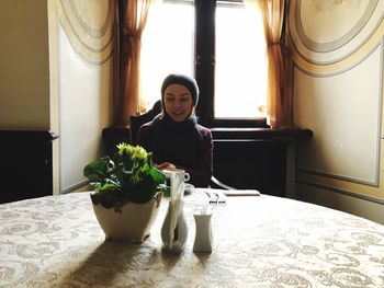 Woman with houseplant on table at home