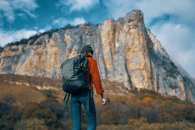 Rear view of man walking on mountain against sky