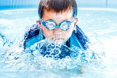 Boy splashing water in swimming pool