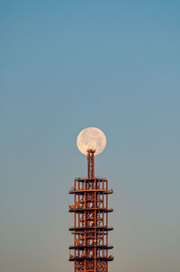 Low angle view of electricity pylon against clear sky