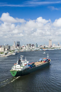 Boats in sea by buildings in city against sky