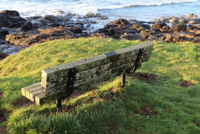 Bench on field by sea