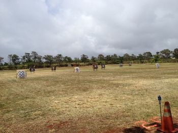 People on grassy field against cloudy sky