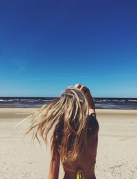 Rear view of woman on beach against sky