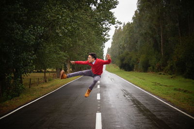 Full length of man jumping on road amidst trees