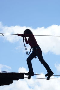 Low angle view of man skateboarding on rope against sky