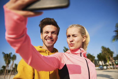 Close-up of couple taking selfie while standing against sky