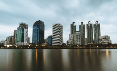 City at waterfront against cloudy sky