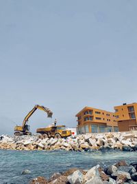 Buildings by sea against clear sky