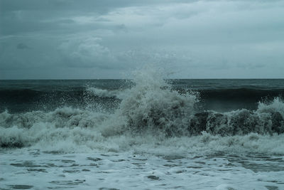 Scenic view of sea waves splashing against sky
