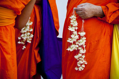 Midsection of monks holding floral garlands