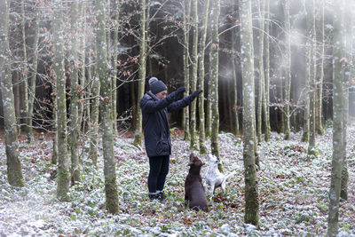 Man with dog standing by tree in forest