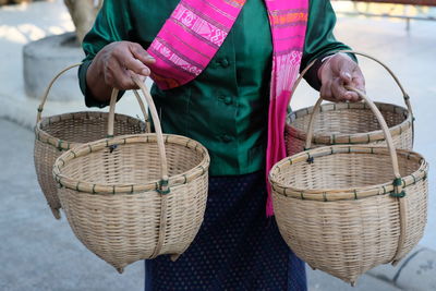 Midsection of man holding wicker baskets while standing outdoors