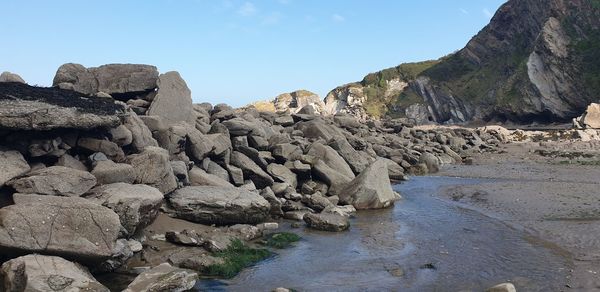 Rock formations on shore against sky