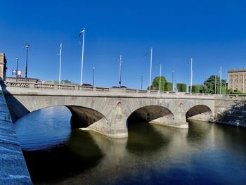 Arch bridge over river against blue sky