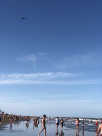 Group of people on beach against blue sky