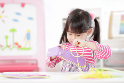 Young girl sweing pad craft using plastic needle and yarn for homeschooling