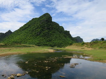 Scenic view of lake by mountain against sky