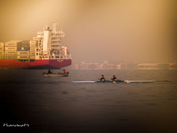 People sailing on sea against sky during sunset